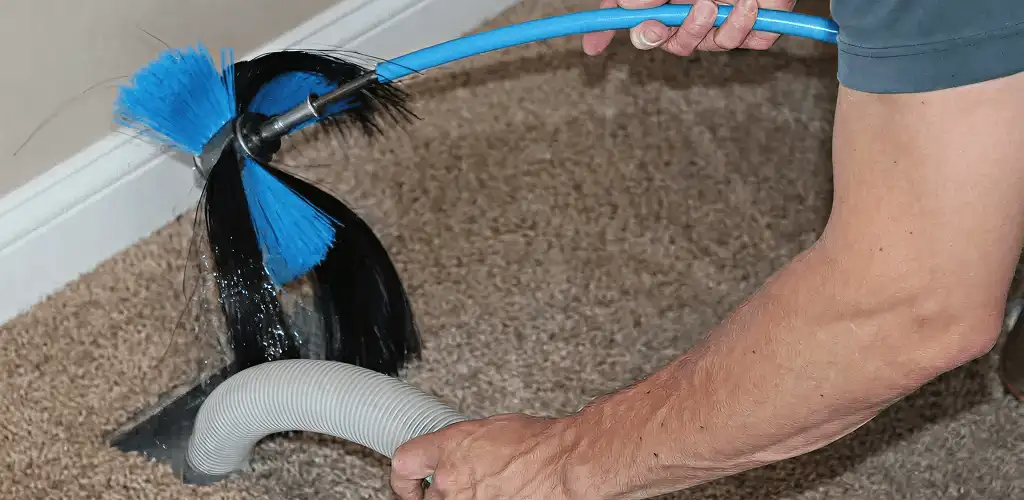 Dryer vent cleaning technician brushing lint from a vent line in Albany, NY