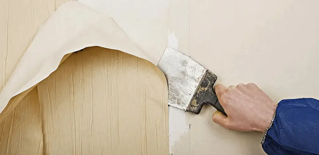 Handyman removing wallpaper with a scraper for wall preparation in Albany, NY