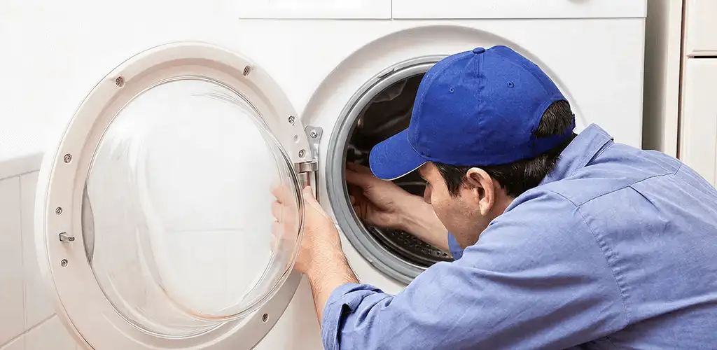 Washing machine repair handyman inspecting a front-load washer drum in Albany, NY
