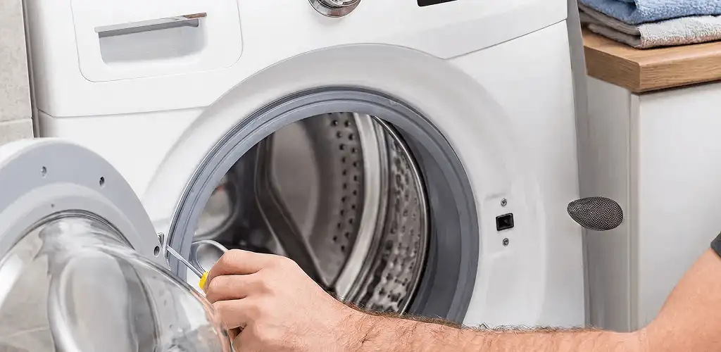 Handyman repairing a front-load washing machine and inspecting the drum in Albany, NY
