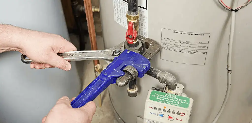 Water heater repair technician tightening the shutoff valve and supply line in Albany, NY